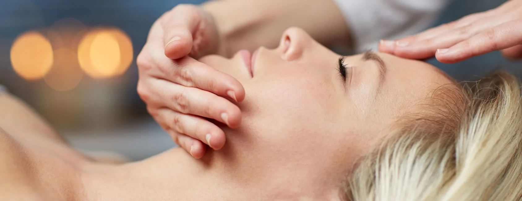 Serene facial massage treatment on a woman by candlelight